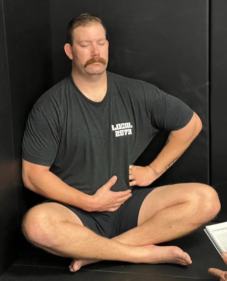 Man sitting cross-legged with eyes closed.